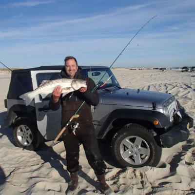 Nick Honachefsky standing in front of a jeep holding a striper