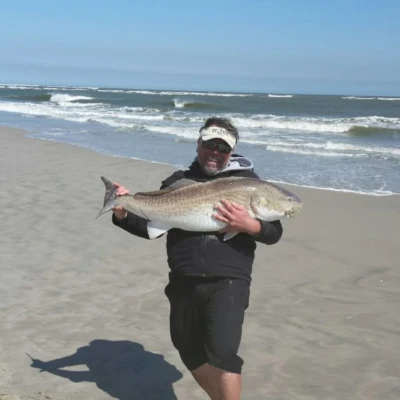 Ryan White standing on the beach holding a redfish