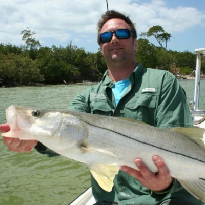 A man on a boat holding a snook