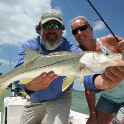 A man holding a snook and a woman holding a rod