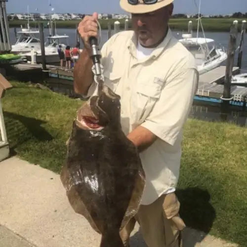 an angler holding a flounder near the docks