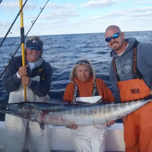 Maureen Klause and two anglers on a boat holding a long fish
